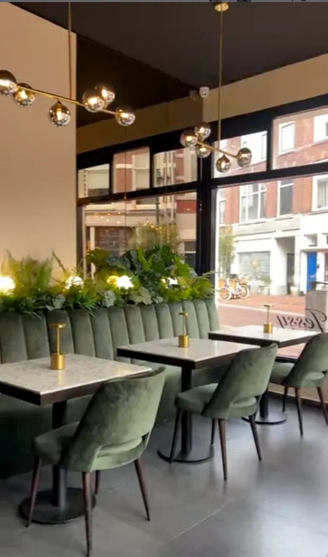De zaak van Jessy aan de Badhuisstraat in Den Haag, met groene stoelen en marmeren tafels
